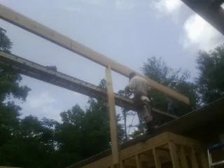Carpenter setting a ridge beam over a new addition frame — Ice Dam Removal by Roofing Brothers in Center Point