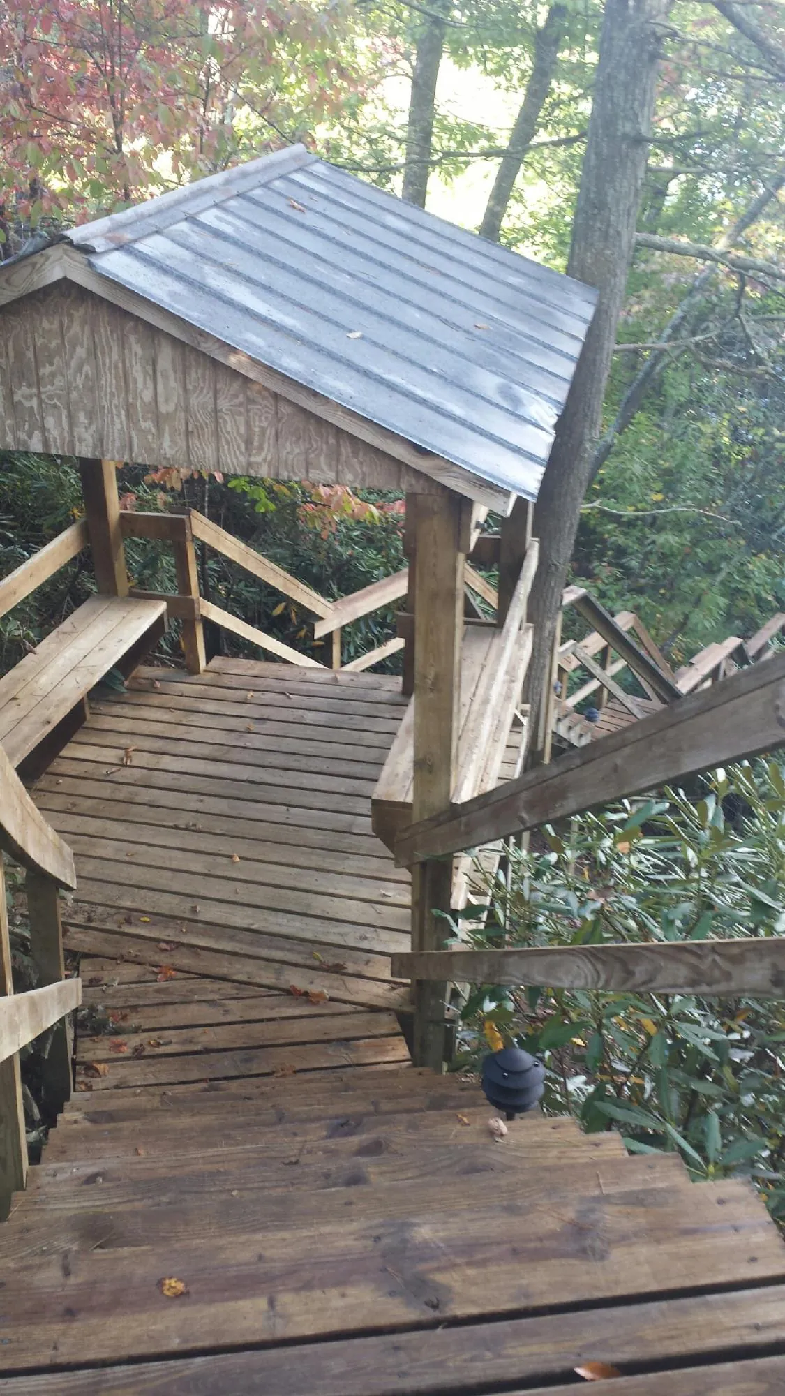 Metal roofed shelter over wooden steps on a wooded walkway — Skylight Repair & Installation work by our crew in Center Point